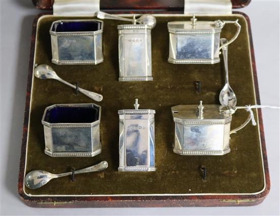 A six-piece silver condiment set, cased with spoons.